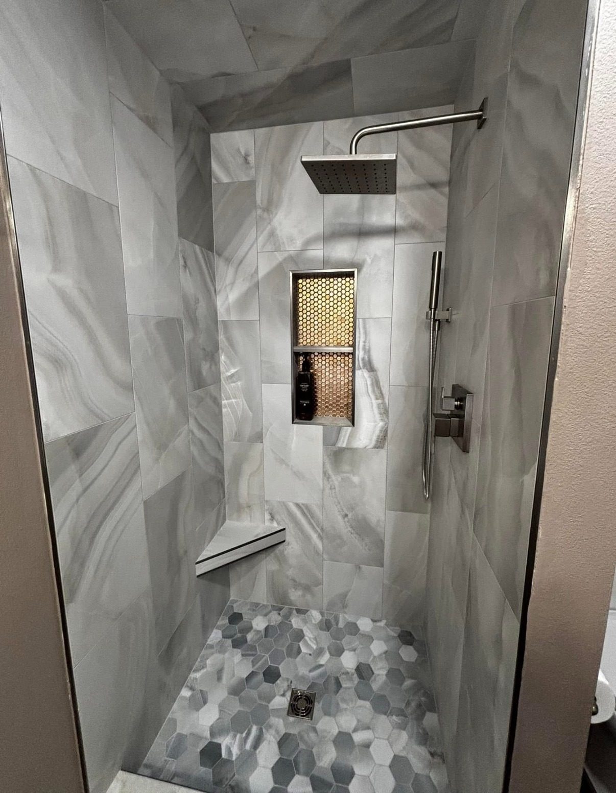Walk-in shower remodel with marble-look tile and gold niche