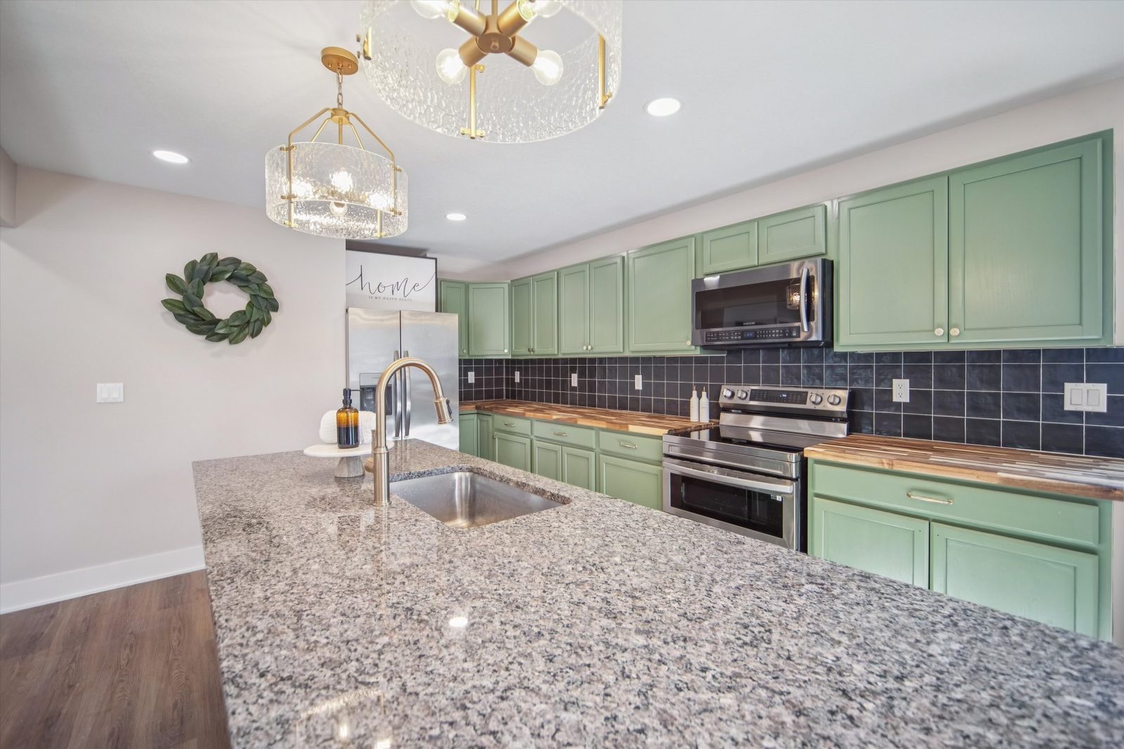 Kitchen remodel with sage cabinets, charcoal tile, and gold fixtures